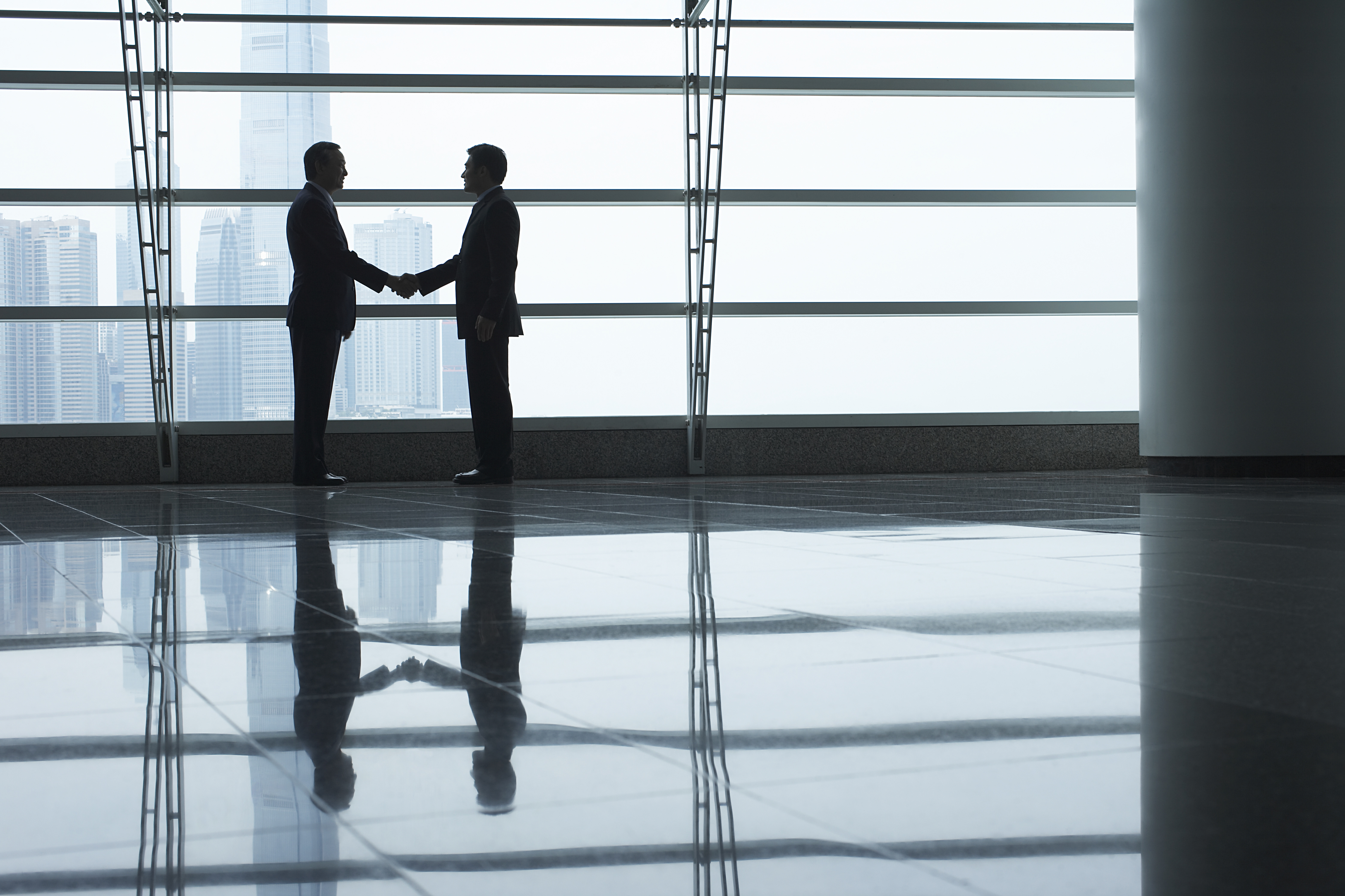 Two men shaking hands in lobby of building