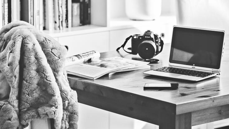 home desk with laptop, camera, and notebook sitting on it