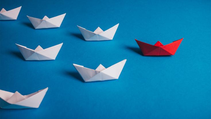 Photo_GEN_OrigamiBoat A picture of origami boats and one red boat is out in front of the others