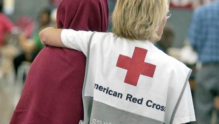 Photo of an American Red Cross Volunteer with their Arm Over Someones Neck Helping Them