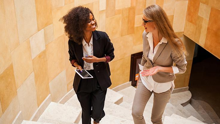 Image of two women talking and walking representing knowledge transfer