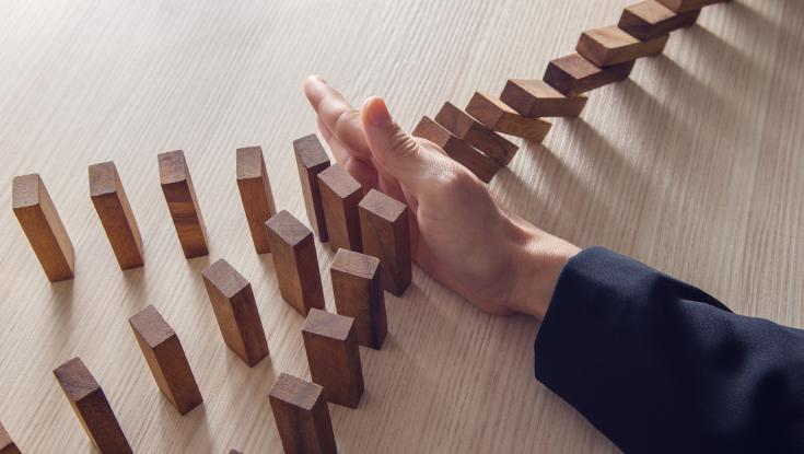 Hand holding up dominos from falling