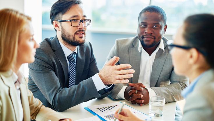 A leader collaborating with others at a table