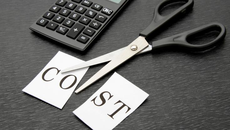 A picture of scissors cutting up a piece of paper that says the word cost on it