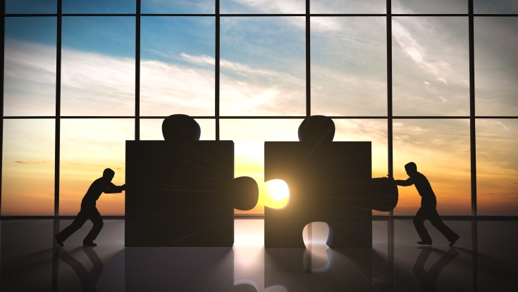 Image of two people pushing together large puzzle pieces