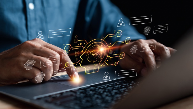 Image of a man's hand typing on a laptop with digital images above the hands.