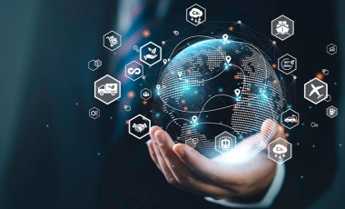 Hand holding a digital globe with supply chain icons surrounding it. 