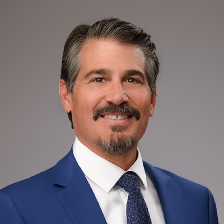 A picture of Harry in a blue suit in front of a gray background