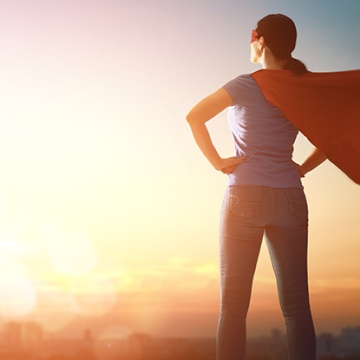 A superhero wearing a cape looking over the city