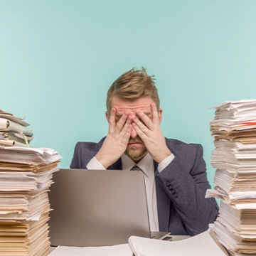 man surrounded by stacks of papers, the three barriers to knowledge transfer 