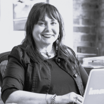 A lady named Cyndee Miller sitting at a desk facing a laptop computer