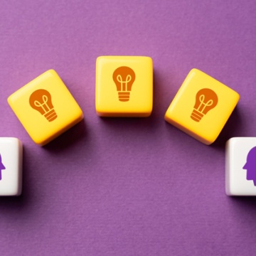 Image of two white plastic cubes with purple heads on them and three yellow cubes in between those cubes with red light bulbs on them.