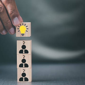 Man stacking wooden blocks with light bulb and people icons