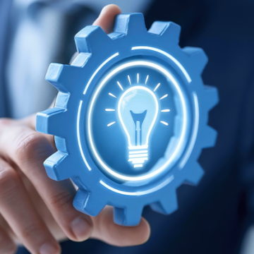A person holds a gear with a glowing lightbulb icon representing innovation, knowledge management, and process improvement.